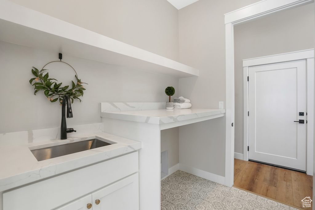 Bar with white cabinetry, light stone countertops, and light hardwood / wood-style flooring