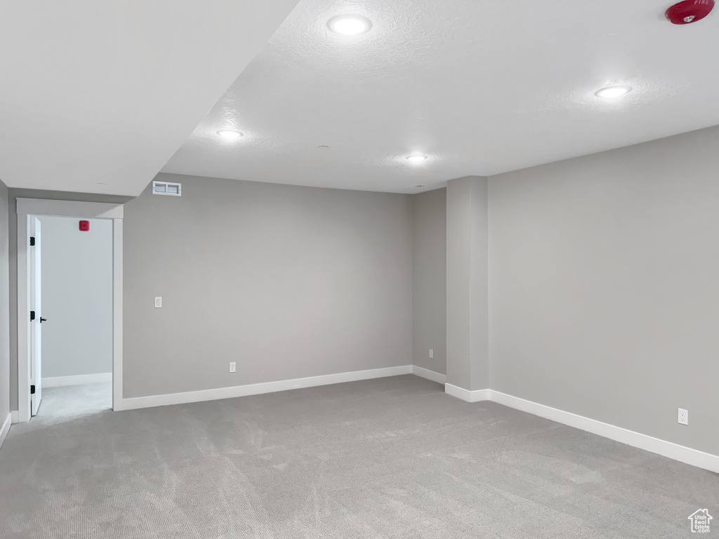 Empty room featuring a textured ceiling and light colored carpet