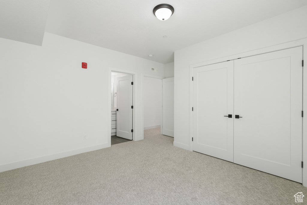 Unfurnished bedroom with light carpet and a closet