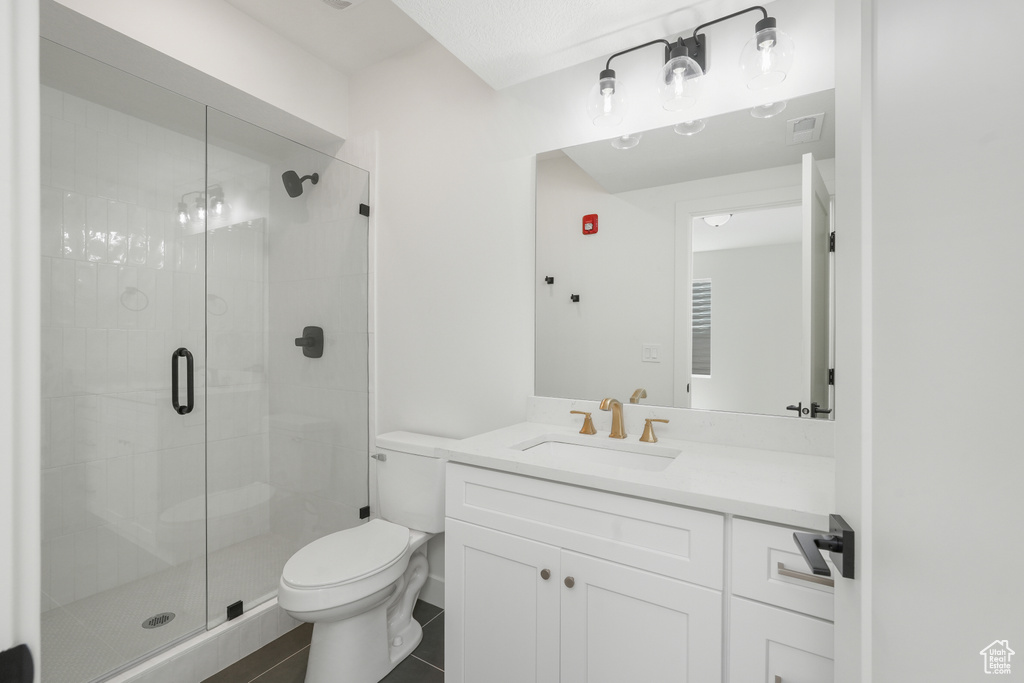 Bathroom with walk in shower, vanity, toilet, and tile patterned floors