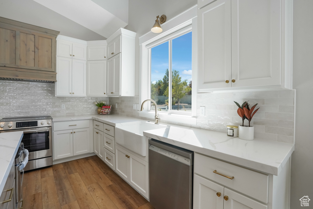 Kitchen featuring appliances with stainless steel finishes, decorative backsplash, white cabinets, dark hardwood / wood-style flooring, and sink