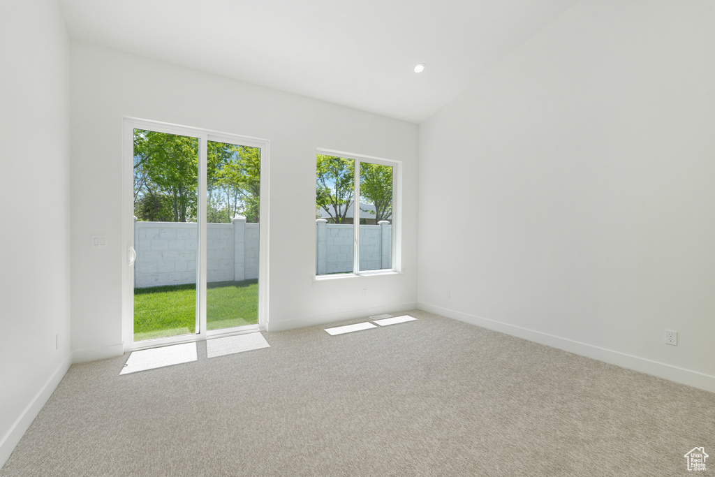 Carpeted spare room featuring lofted ceiling