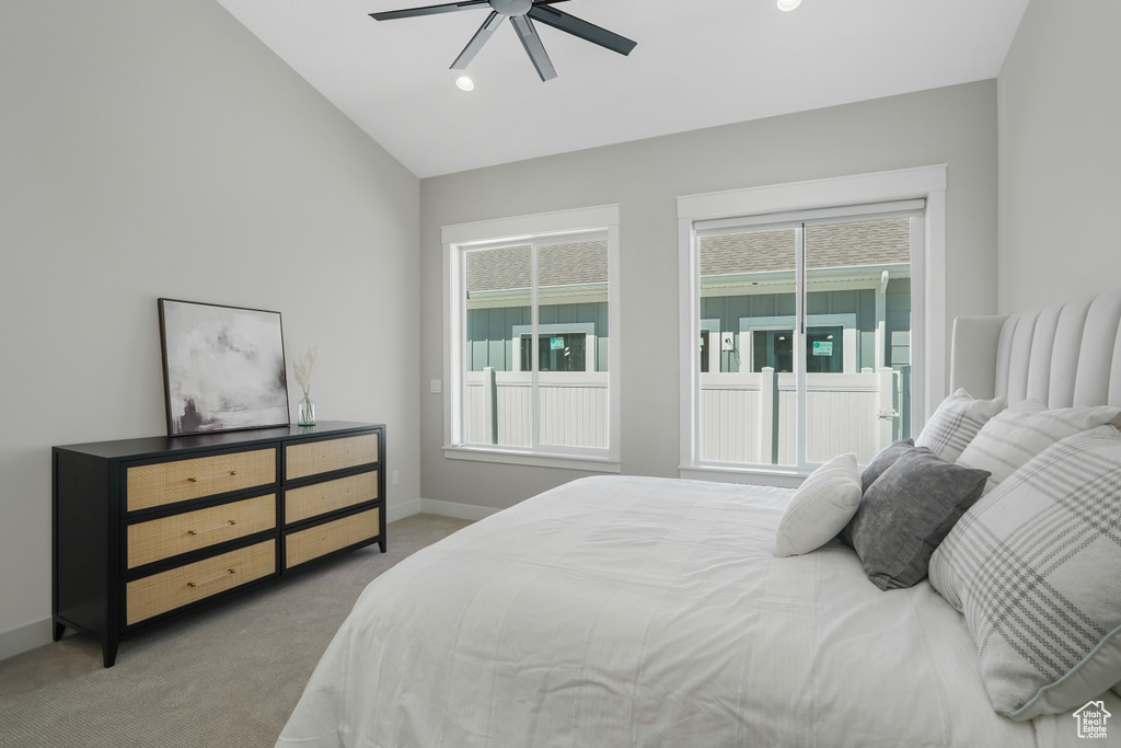 Carpeted bedroom with vaulted ceiling, ceiling fan, and multiple windows