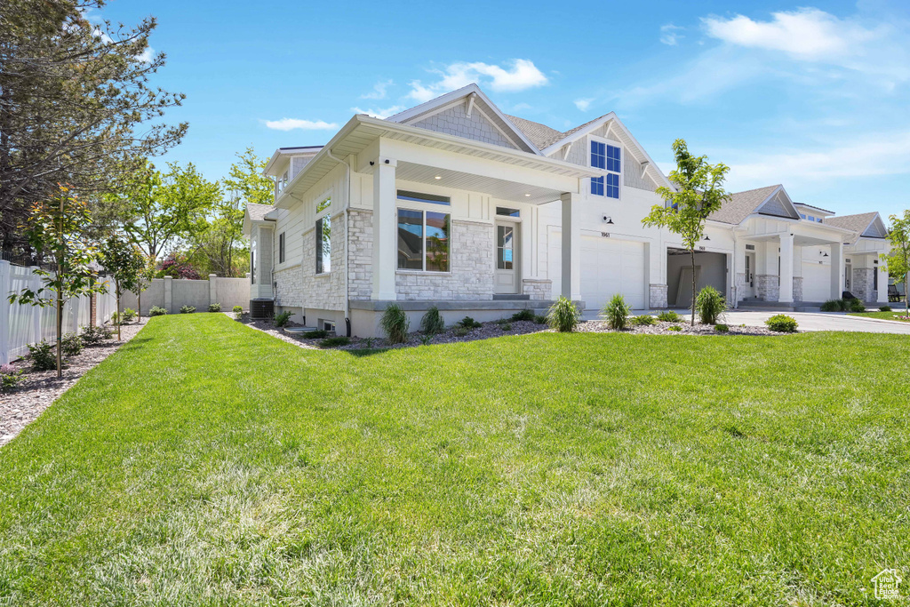 View of front of house featuring cooling unit, a garage, and a front yard