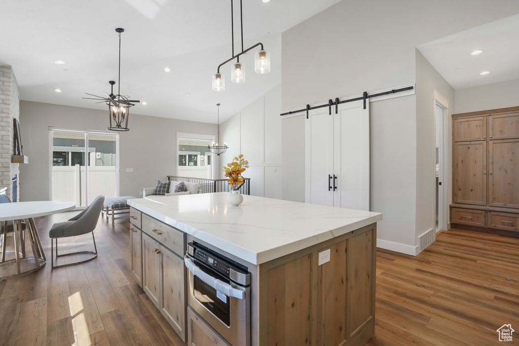 Kitchen featuring hanging light fixtures, a barn door, stainless steel oven, dark hardwood / wood-style floors, and a chandelier