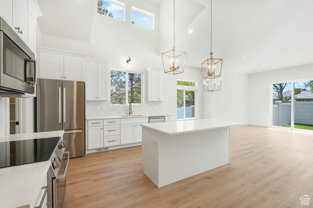 Kitchen featuring decorative light fixtures, stainless steel appliances, a wealth of natural light, and white cabinetry