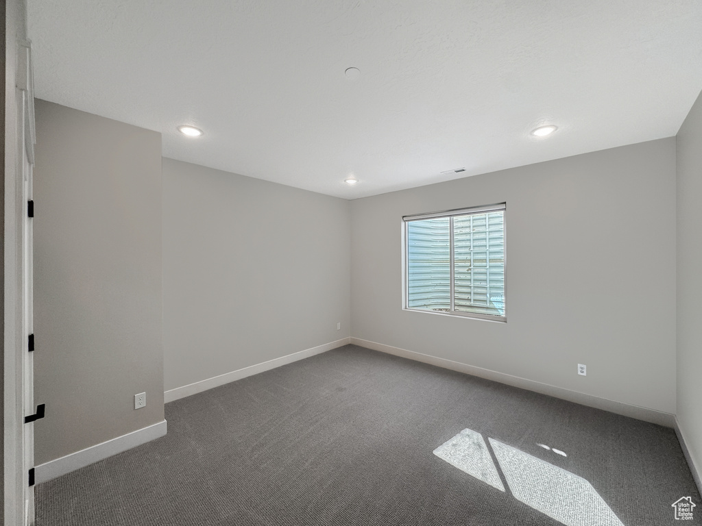 Empty room featuring dark colored carpet