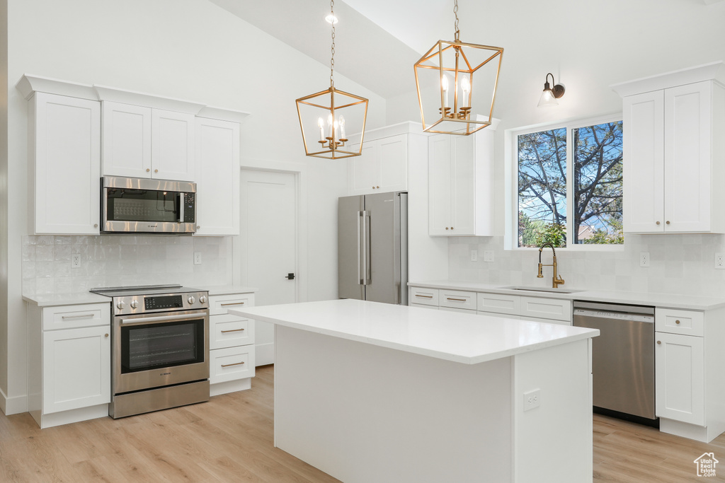 Kitchen with a chandelier, sink, white cabinetry, hanging light fixtures, and stainless steel appliances