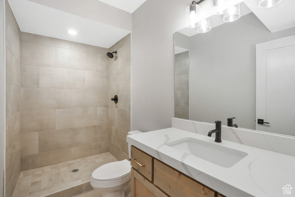 Bathroom with a tile shower, vanity, and toilet