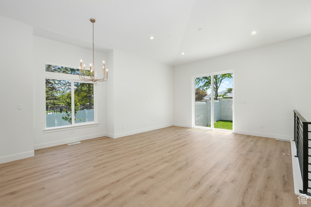 Unfurnished living room featuring a notable chandelier and light hardwood / wood-style floors