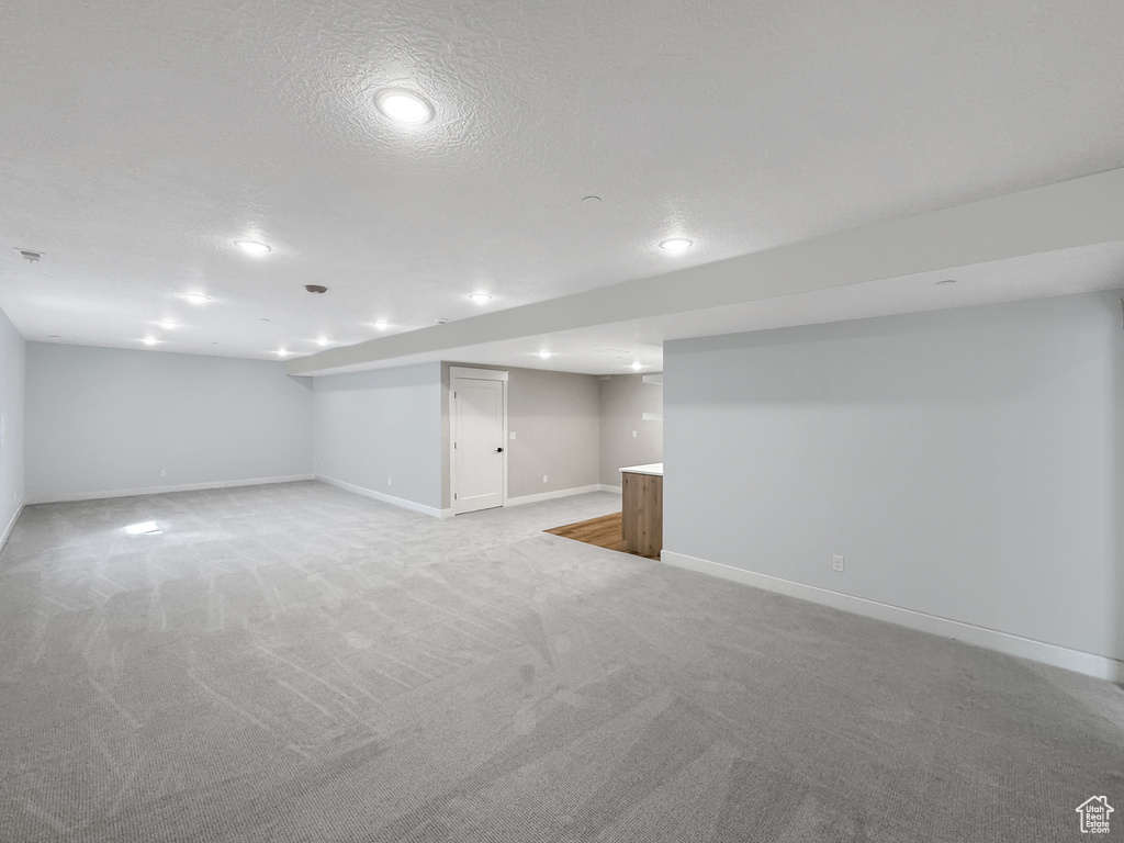 Basement featuring light colored carpet and a textured ceiling