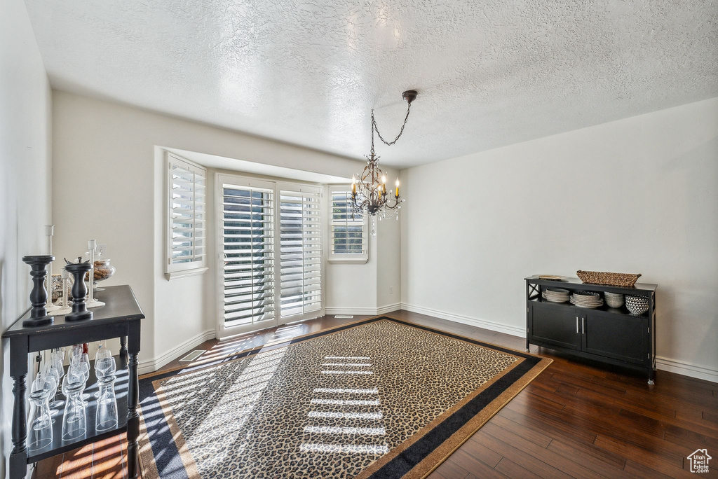 Interior space featuring a textured ceiling, dark hardwood / wood-style floors, and a notable chandelier