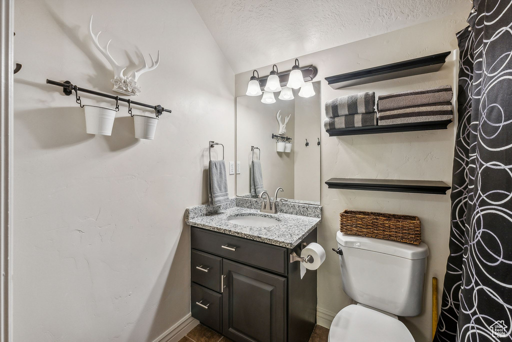 Bathroom with a textured ceiling, vanity, and toilet