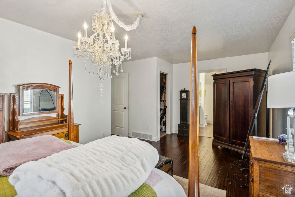 Bedroom with a notable chandelier, a closet, dark wood-type flooring, and a textured ceiling