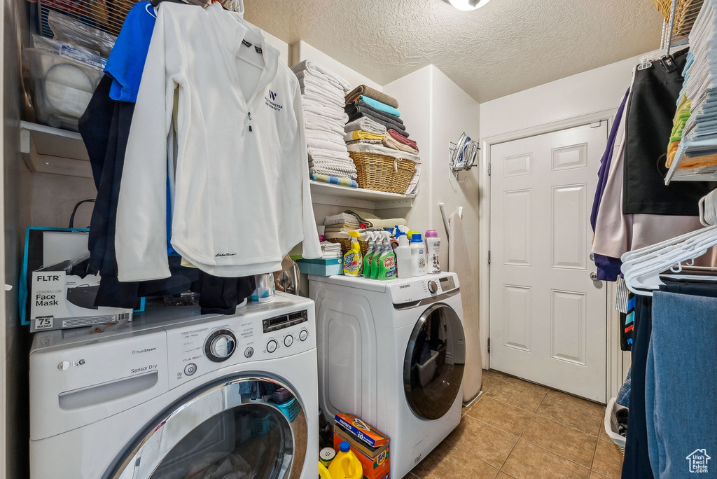 Laundry room with a textured ceiling, washing machine and dryer, and light tile patterned floors