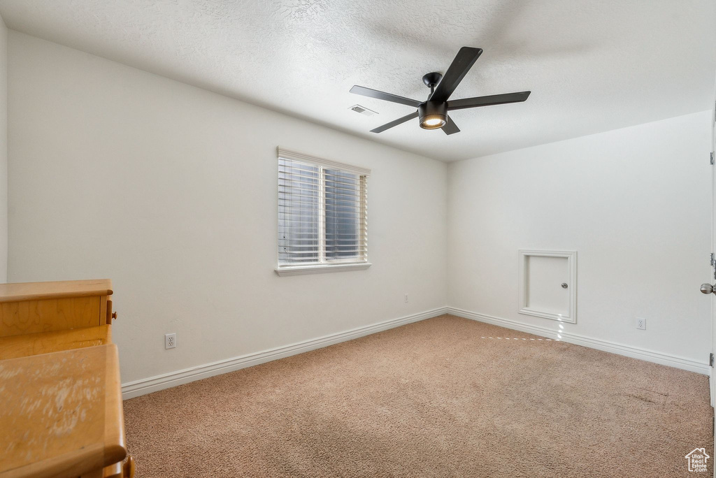 Carpeted spare room featuring a textured ceiling and ceiling fan