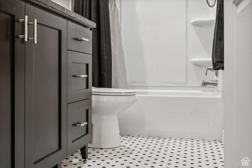 Bathroom with shower / tub combo with curtain, tile patterned floors, and toilet