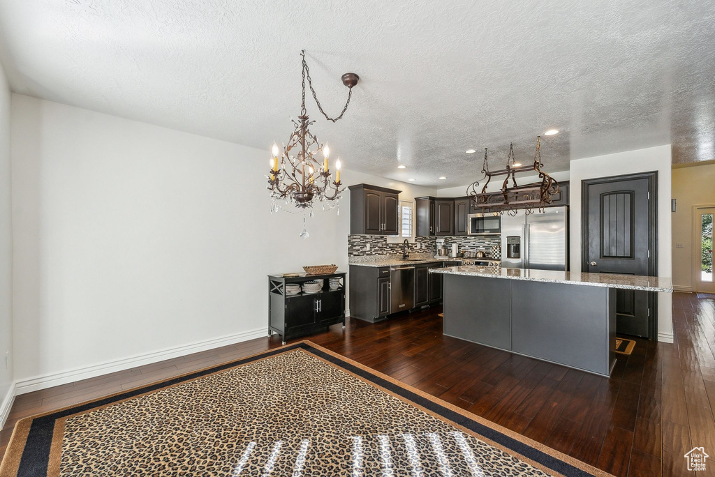 Kitchen featuring a kitchen island, stainless steel appliances, a textured ceiling, dark brown cabinets, and dark hardwood / wood-style floors