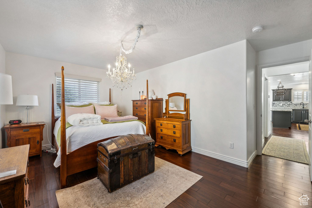 Bedroom with a chandelier, a textured ceiling, sink, and dark hardwood / wood-style flooring