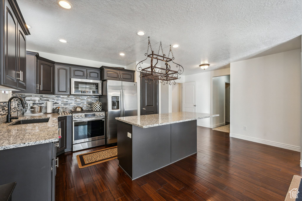 Kitchen featuring a kitchen island, sink, stainless steel appliances, and dark hardwood / wood-style flooring