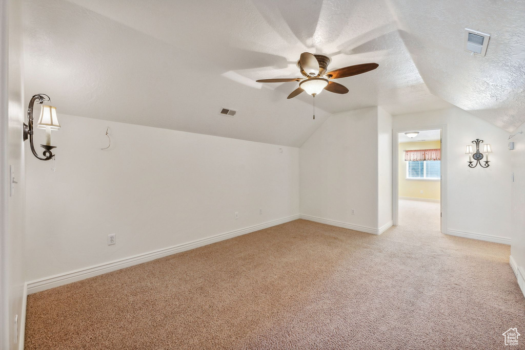 Bonus room with a textured ceiling, lofted ceiling, carpet flooring, and ceiling fan