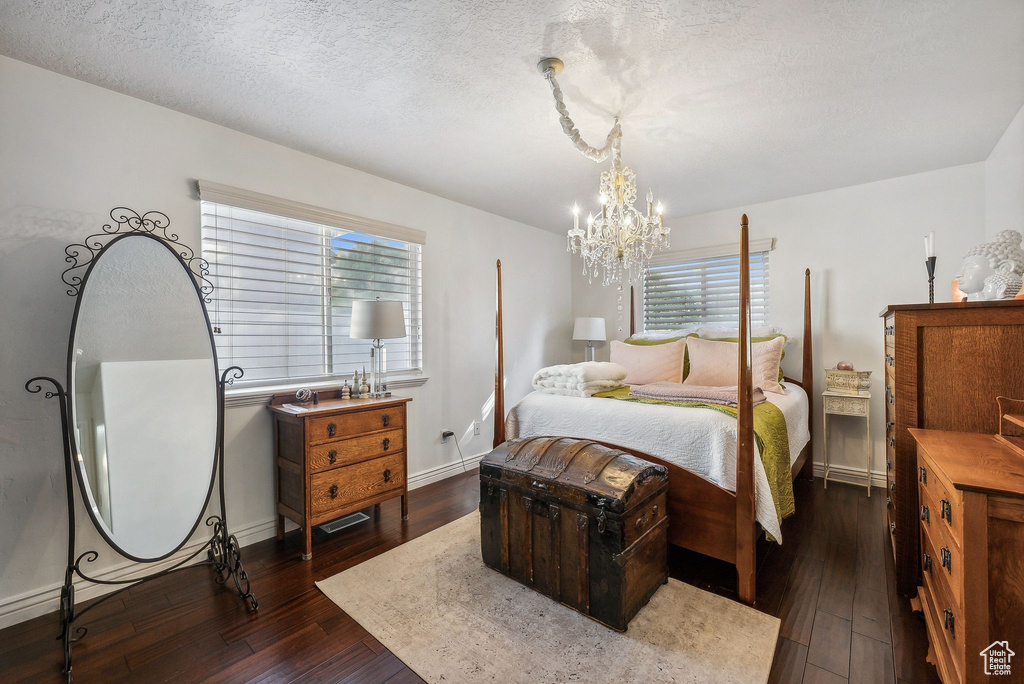 Bedroom featuring a notable chandelier, a textured ceiling, dark hardwood / wood-style flooring, and multiple windows