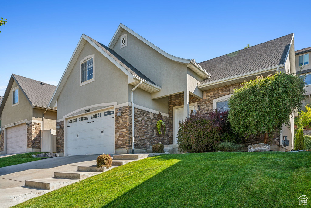 View of front of property featuring a garage and a front lawn