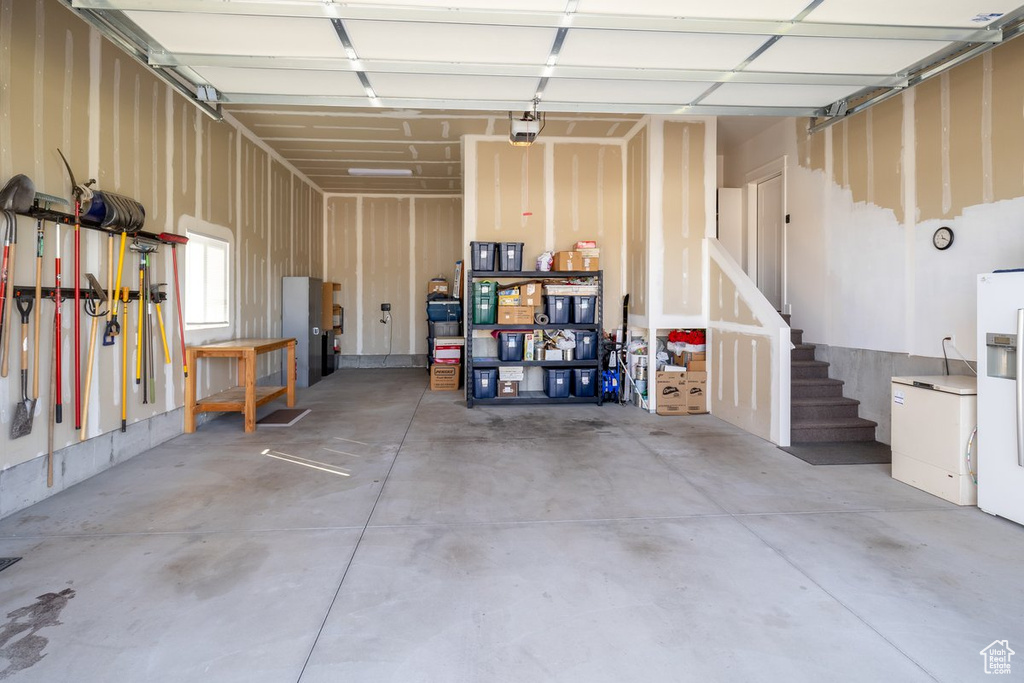 Garage featuring white fridge with ice dispenser and a garage door opener