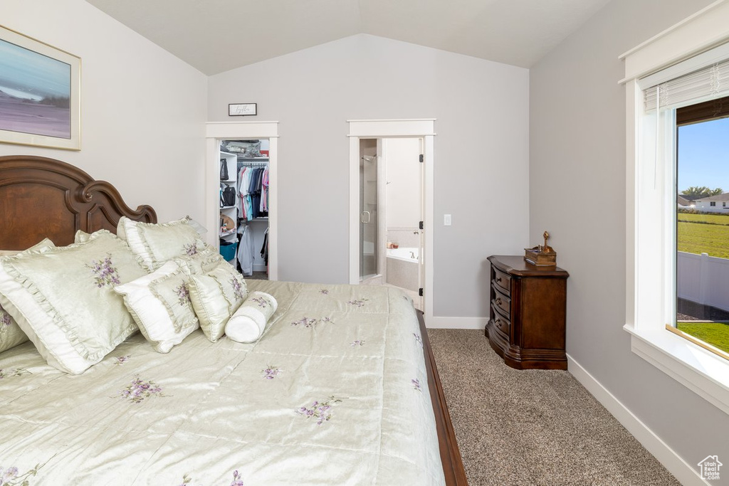 Bedroom featuring vaulted ceiling, carpet floors, a closet, a walk in closet, and ensuite bath