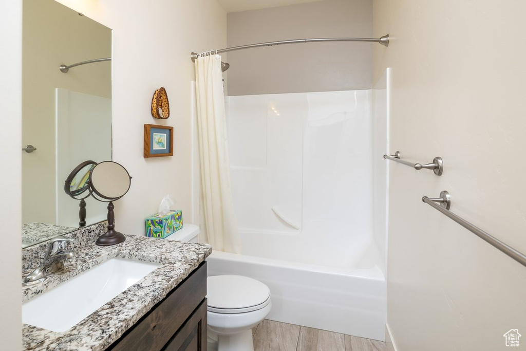 Full bathroom featuring vanity, shower / bath combo with shower curtain, and toilet