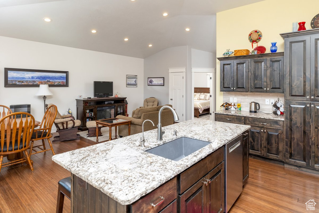 Kitchen with vaulted ceiling, backsplash, a center island with sink, dark hardwood / wood-style floors, and sink