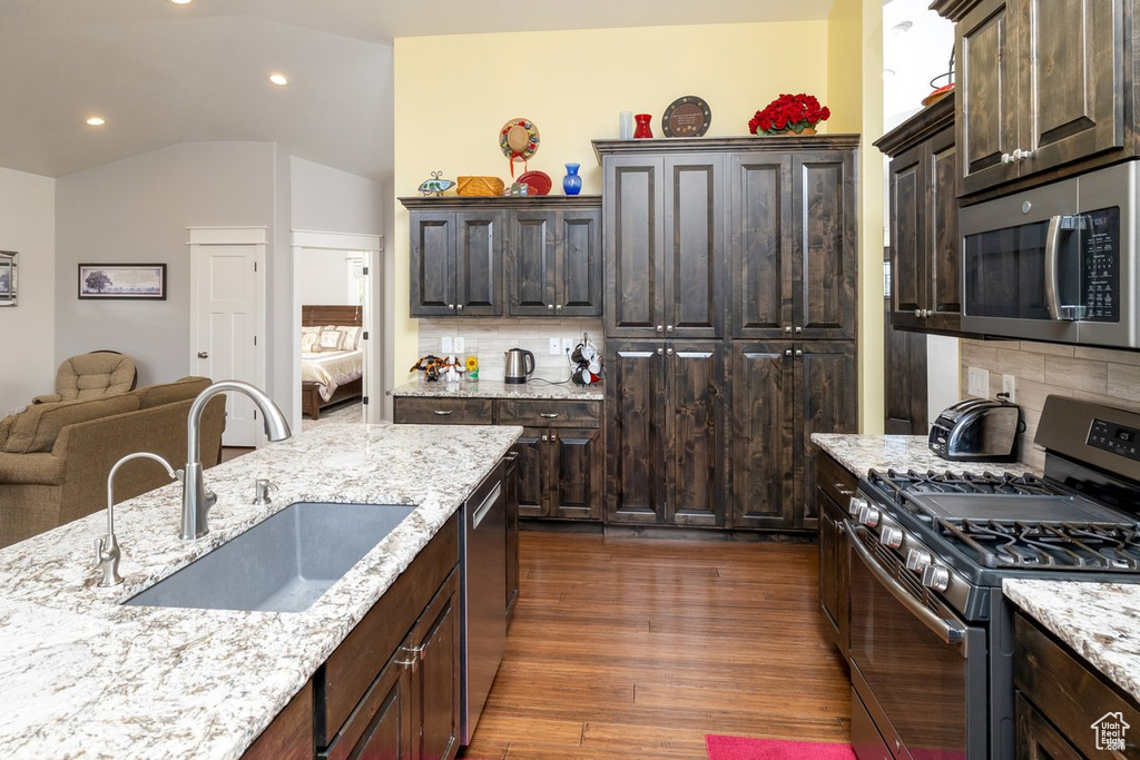 Kitchen featuring dark brown cabinets, dark hardwood / wood-style floors, sink, decorative backsplash, and appliances with stainless steel finishes