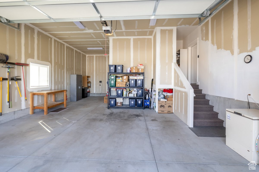 Garage featuring a garage door opener and white refrigerator