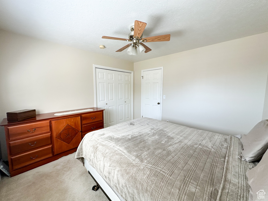 Carpeted bedroom featuring a closet, ceiling fan, and a textured ceiling