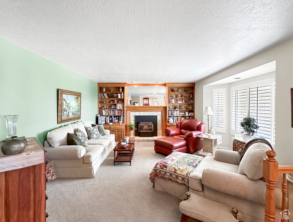 Carpeted living room with a tiled fireplace and a textured ceiling