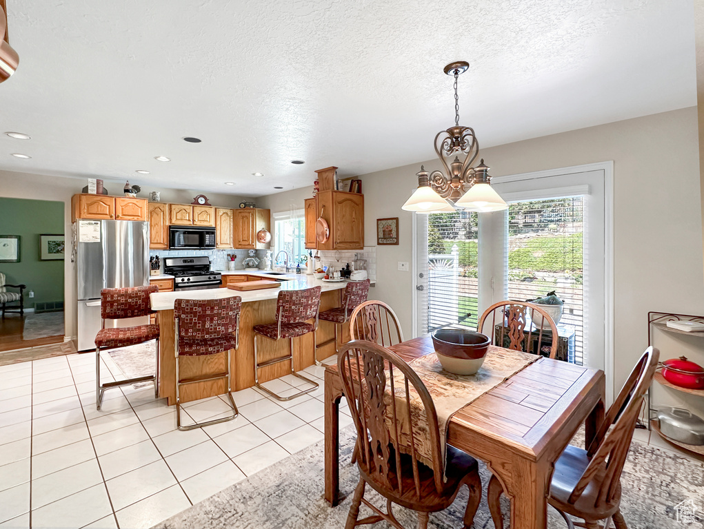 Tiled dining room featuring an inviting chandelier, a textured ceiling, and sink