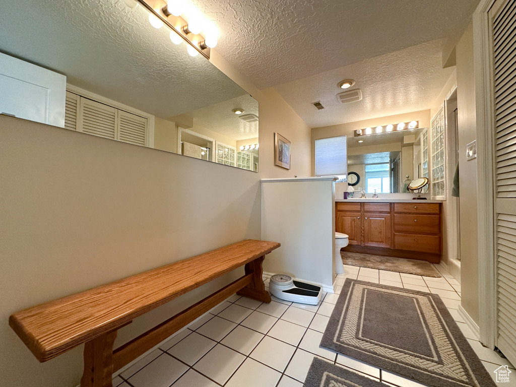 Bathroom with a shower, vanity, a textured ceiling, toilet, and tile patterned floors