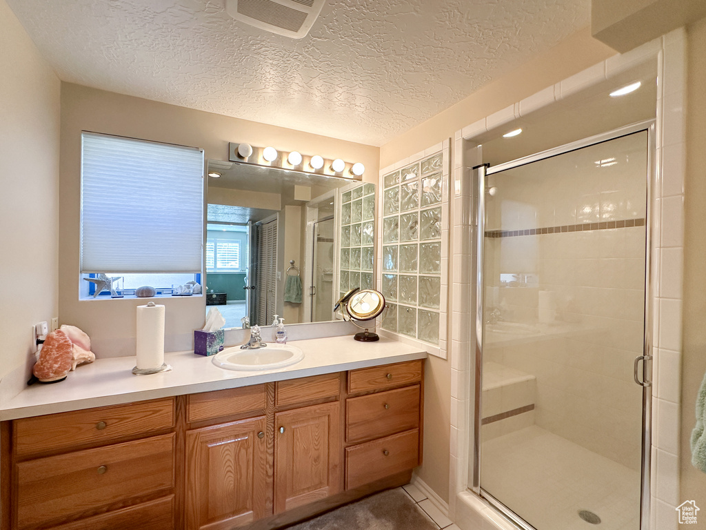 Bathroom featuring vanity, a textured ceiling, and a shower with door