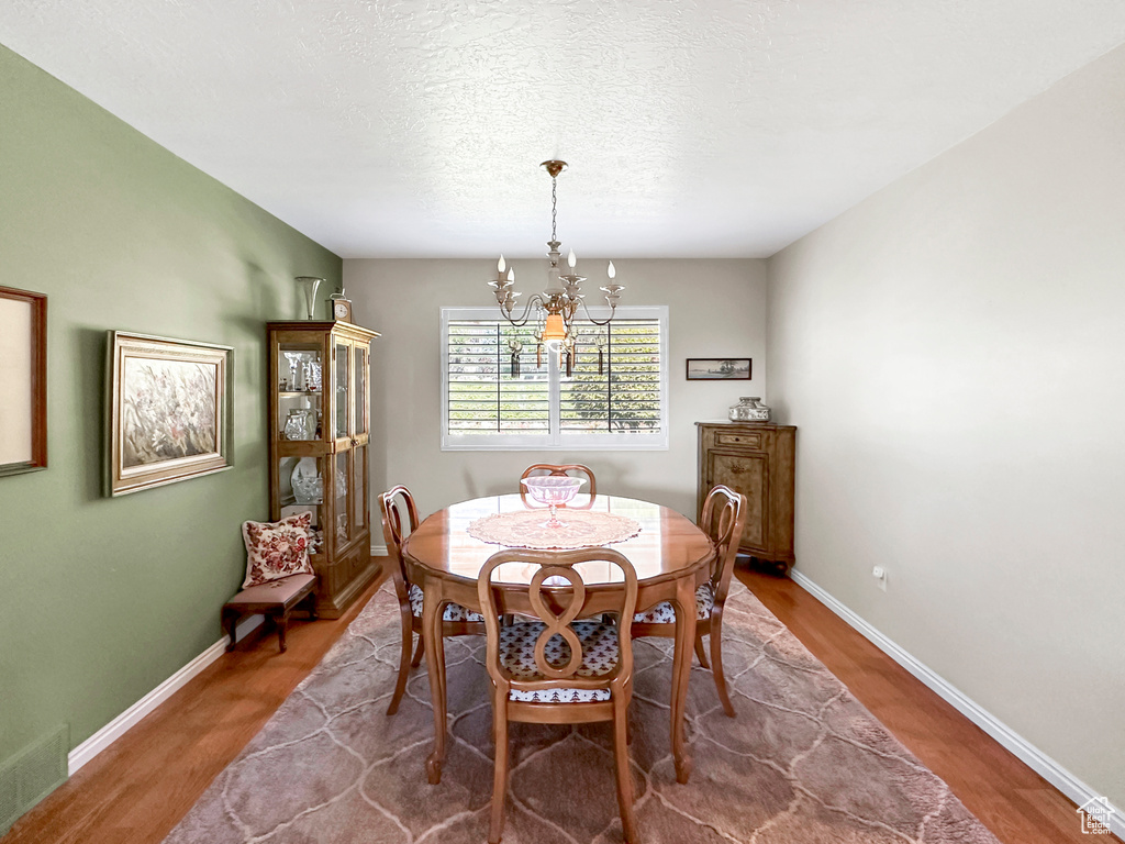 Dining room featuring a chandelier, a textured ceiling, and hardwood / wood-style floors