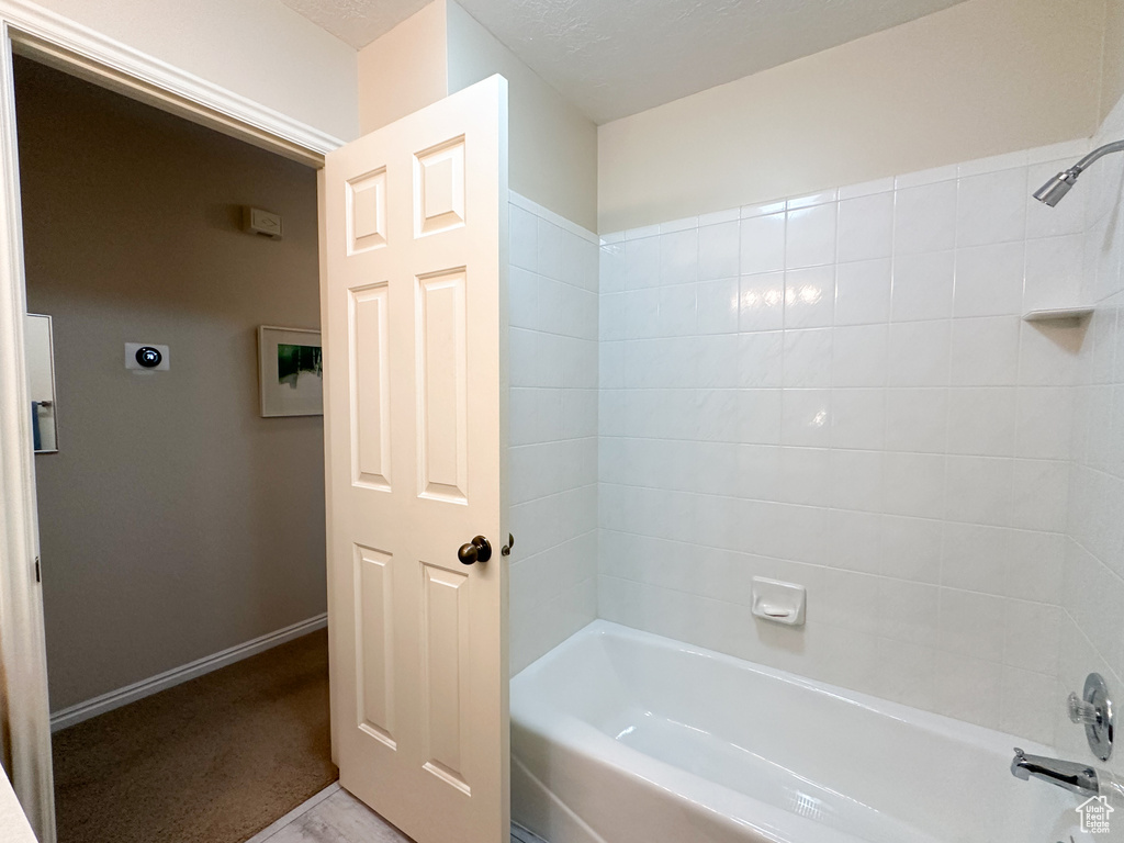 Bathroom with tiled shower / bath and a textured ceiling