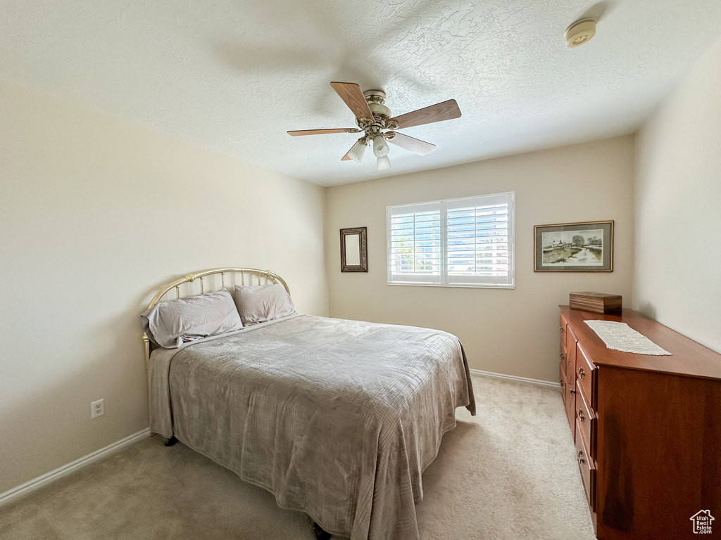 Carpeted bedroom featuring ceiling fan and a textured ceiling