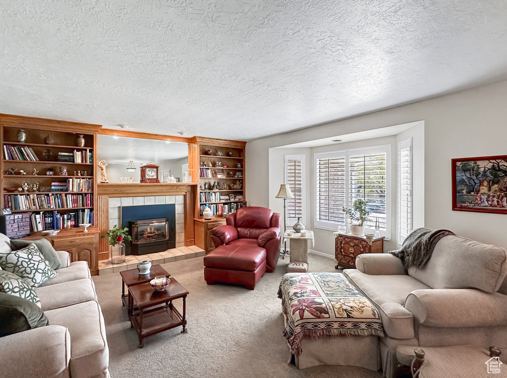 Living room with a textured ceiling, a tile fireplace, and carpet floors