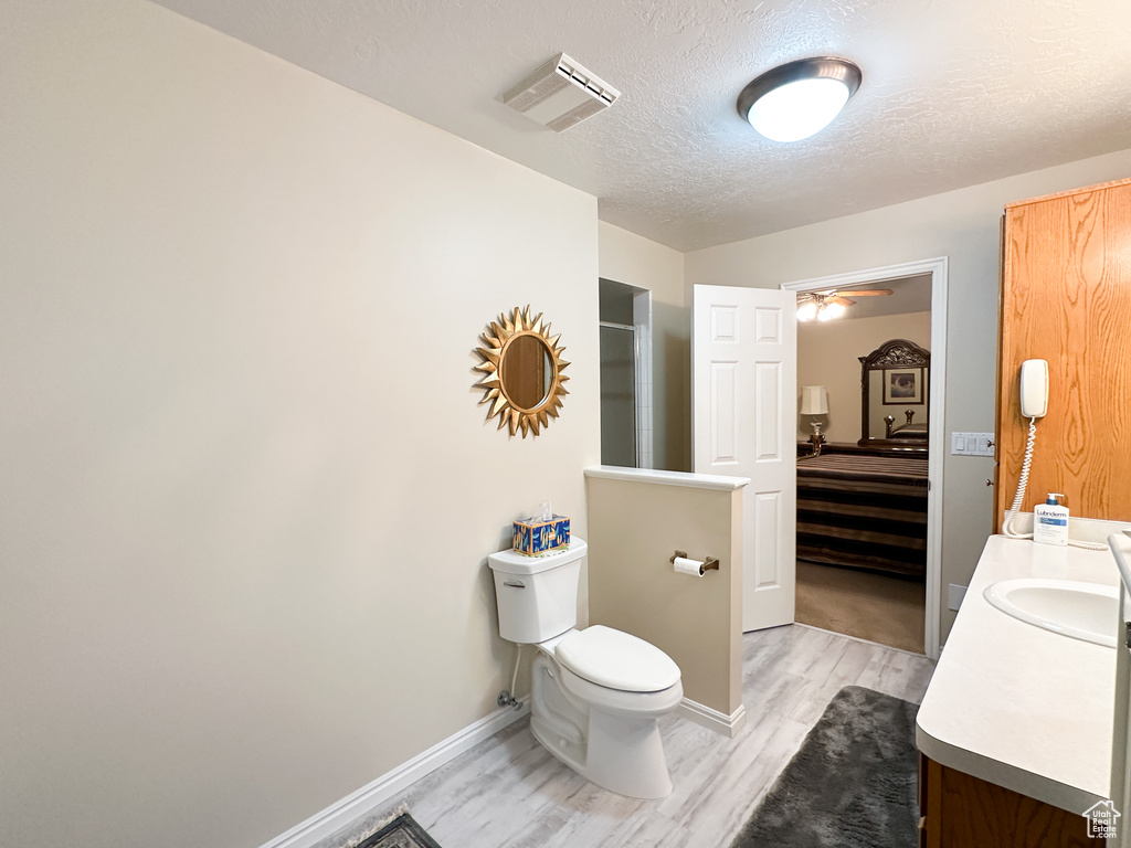 Bathroom with vanity, walk in shower, a textured ceiling, toilet, and hardwood / wood-style floors