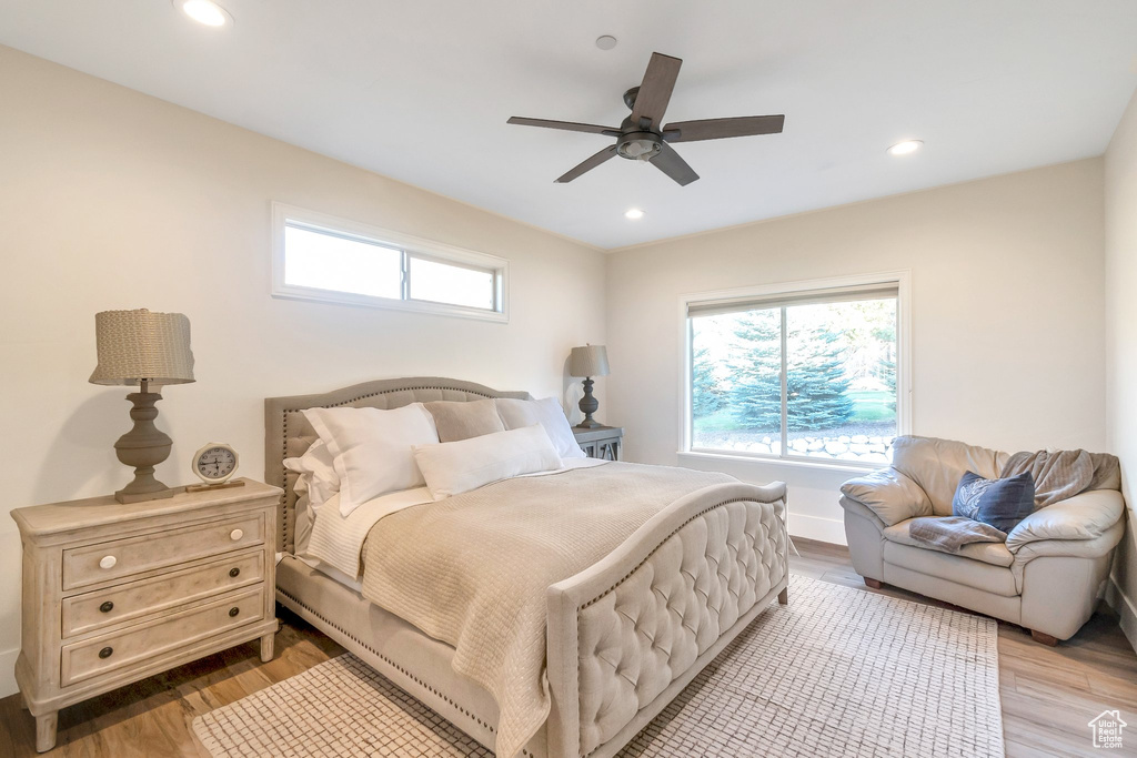 Bedroom featuring light hardwood / wood-style floors, multiple windows, and ceiling fan