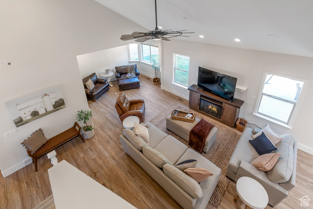 Living room with light hardwood / wood-style flooring, ceiling fan, and high vaulted ceiling