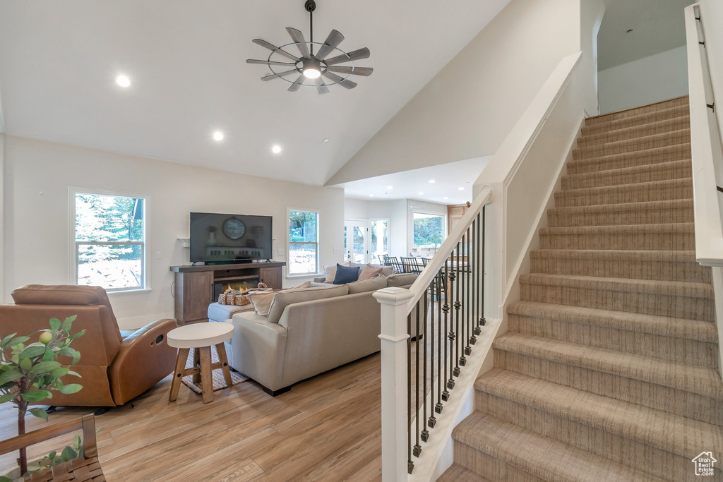 Living room with light hardwood / wood-style floors, ceiling fan, and high vaulted ceiling