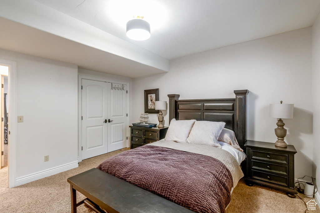 Bedroom with light colored carpet and a closet