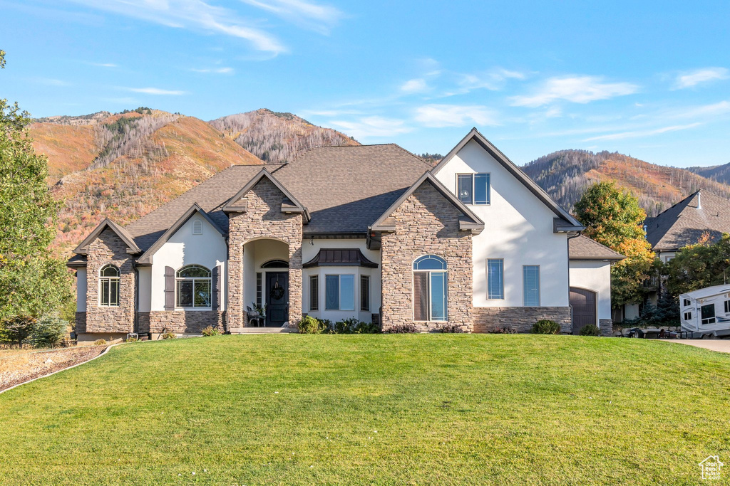 View of front of property with a mountain view and a front lawn