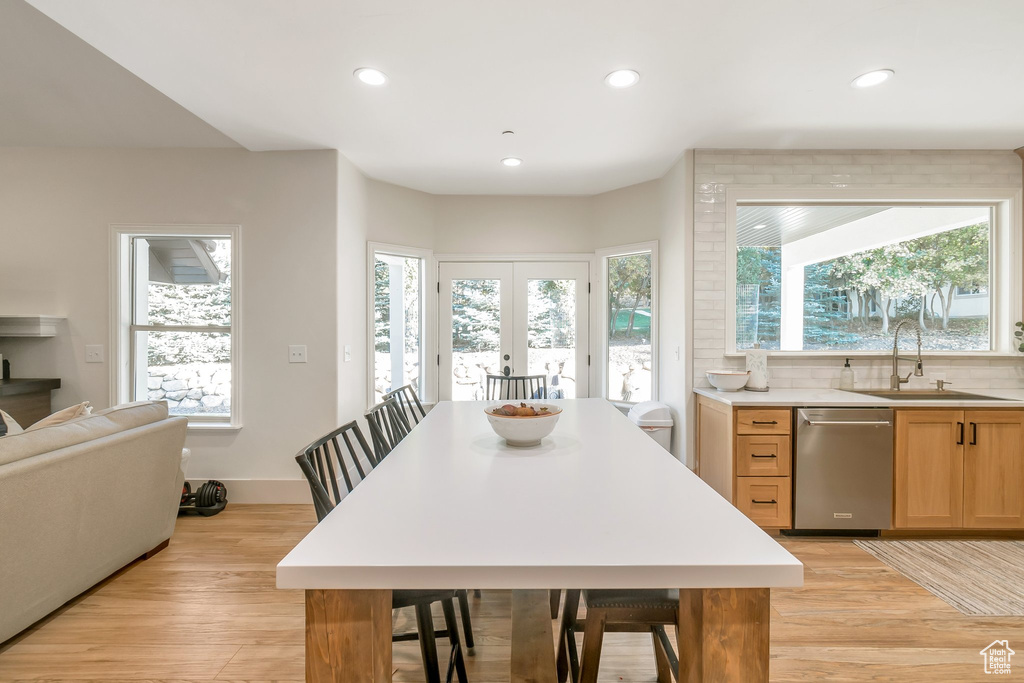 Kitchen featuring stainless steel dishwasher, tasteful backsplash, light hardwood / wood-style flooring, and a wealth of natural light