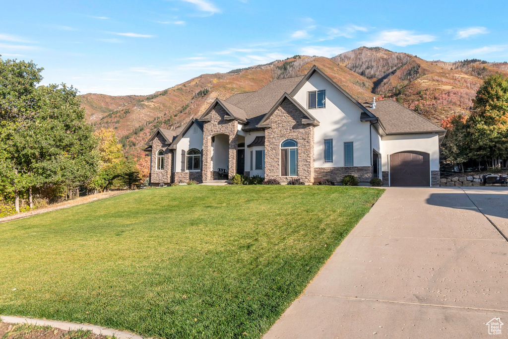 View of front of property with a mountain view, a garage, and a front lawn